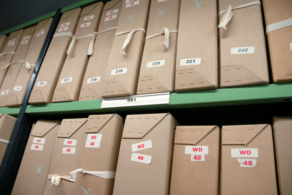 Rows of labeled archive boxes stored on metal shelving at The National Archives.