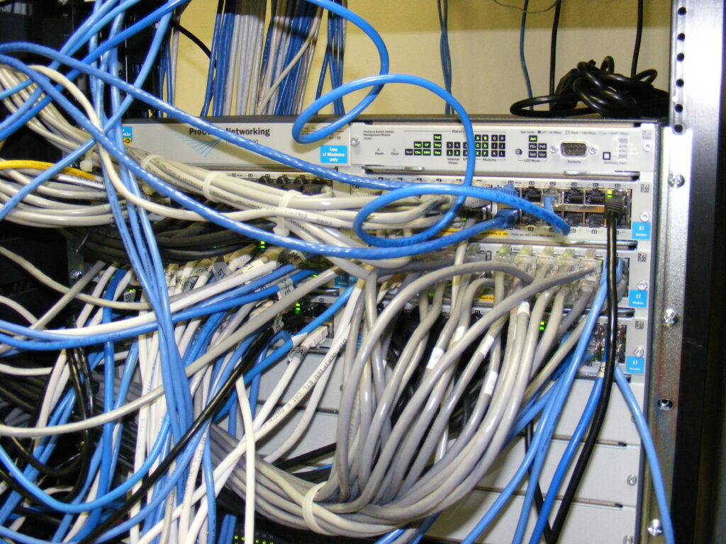 HP ProCurve network switch surrounded by connected Cat5 cables.
